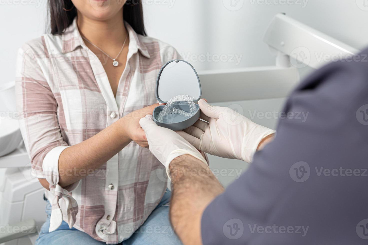 Crop anonymous woman taking aligners box from dentist photo