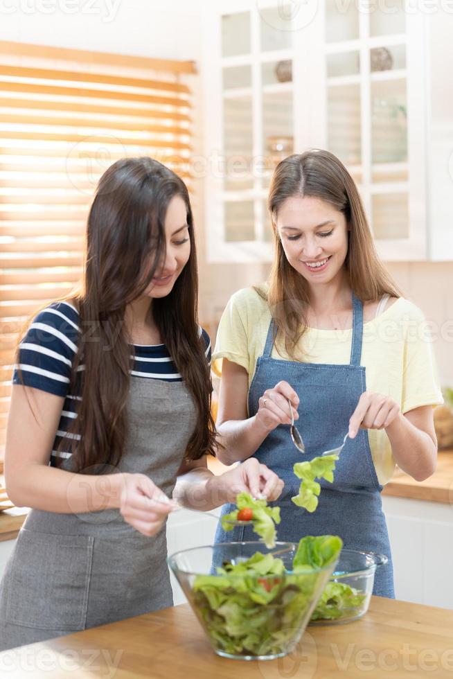 contento y sonrisa lesbiana Pareja Cocinando ensalada en el cocina. ensalada en vaso cuenco con dulce sonrisa mientras Cocinando juntos. orgullo mes a promover igualdad y diferencias de homosexual foto