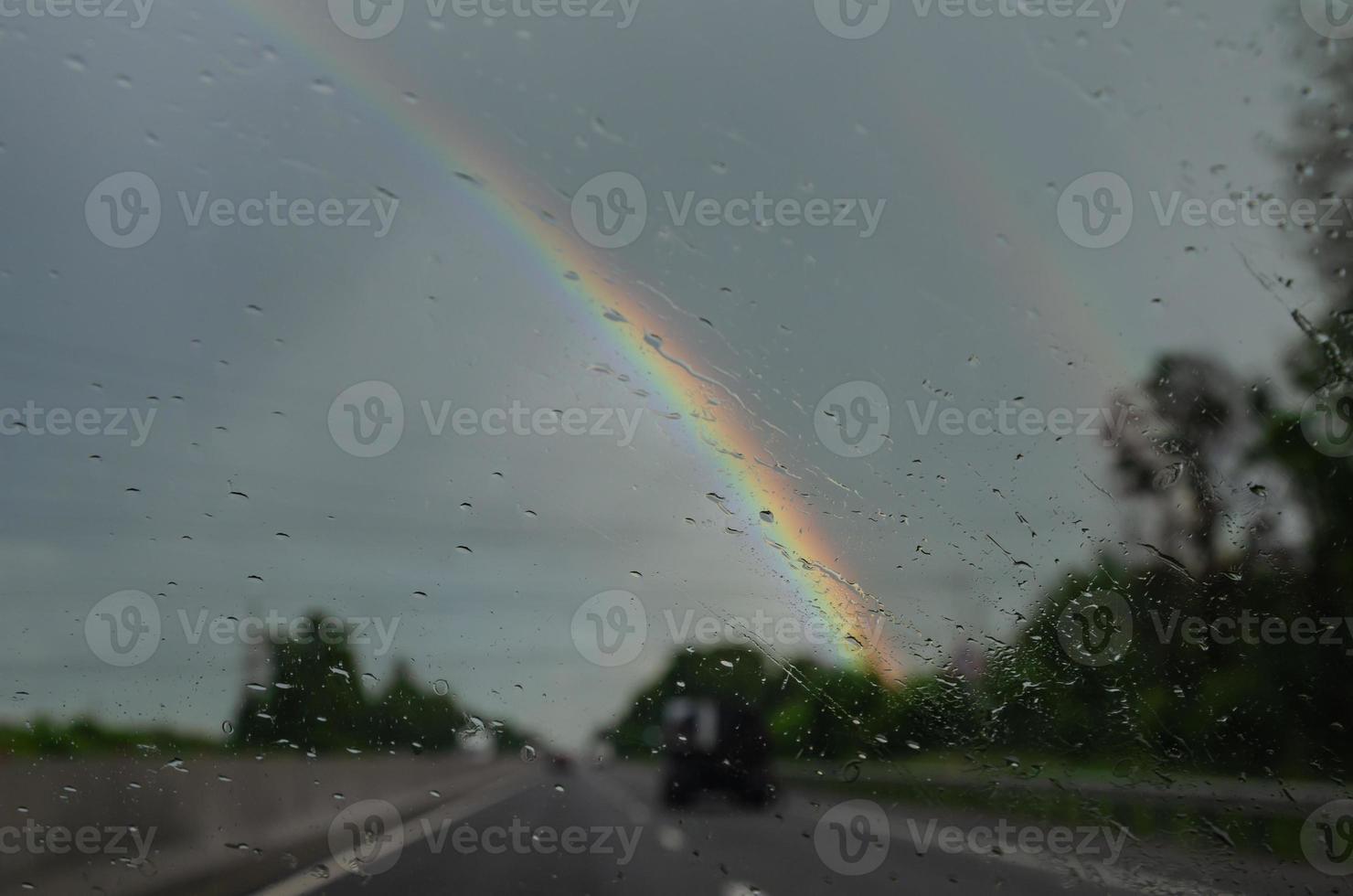 borroso ver desde el coche ventana en un arco iris en el lluvia foto