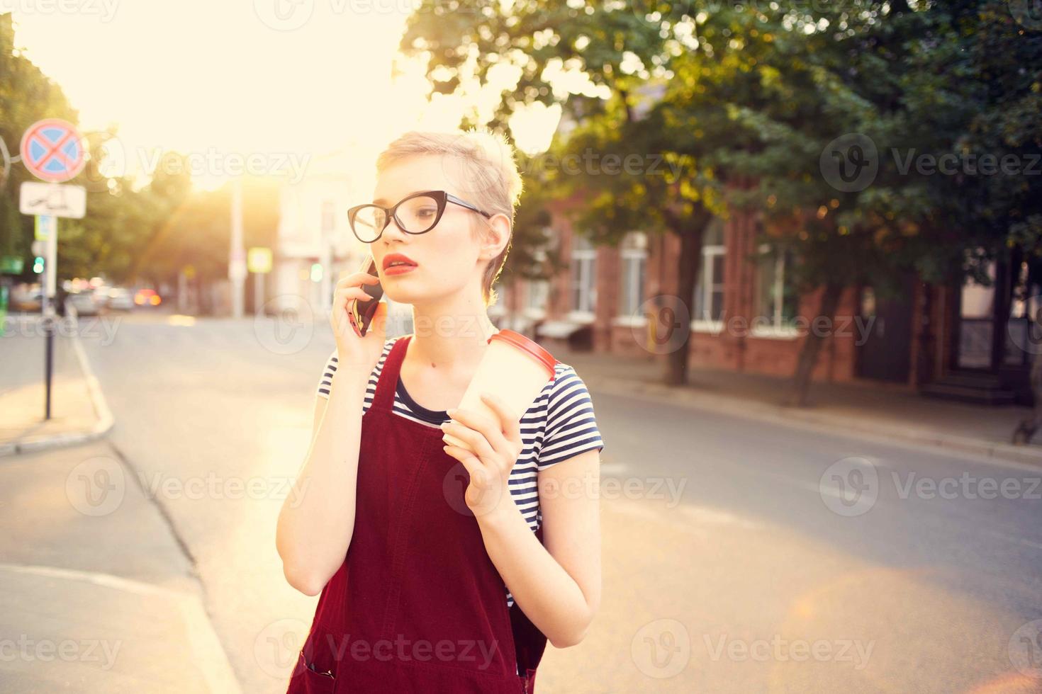 mujer con corto pelo en el calle hablando en el teléfono un taza de bebida foto