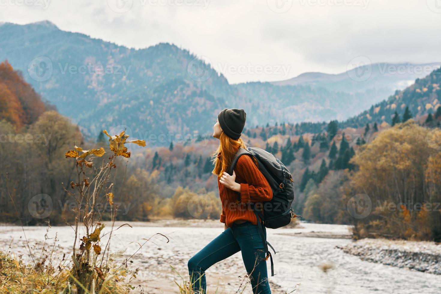 woman in a jeans sweater with a backpack rest in the mountains near the river in nature photo