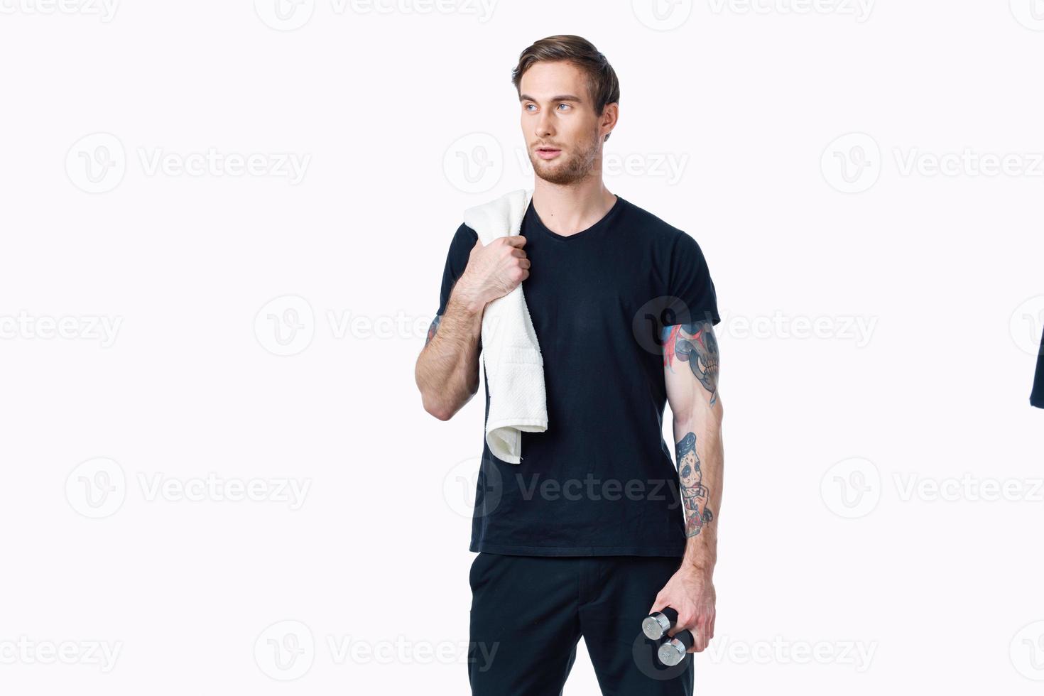 male athlete in a t-shirt with dumbbells in his hand and a towel on his shoulder photo