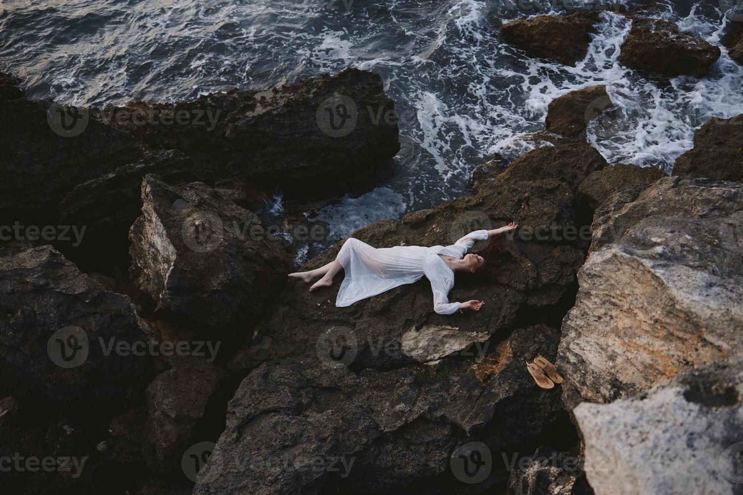 sensual woman lying on her back on a rocky seashore view from above photo
