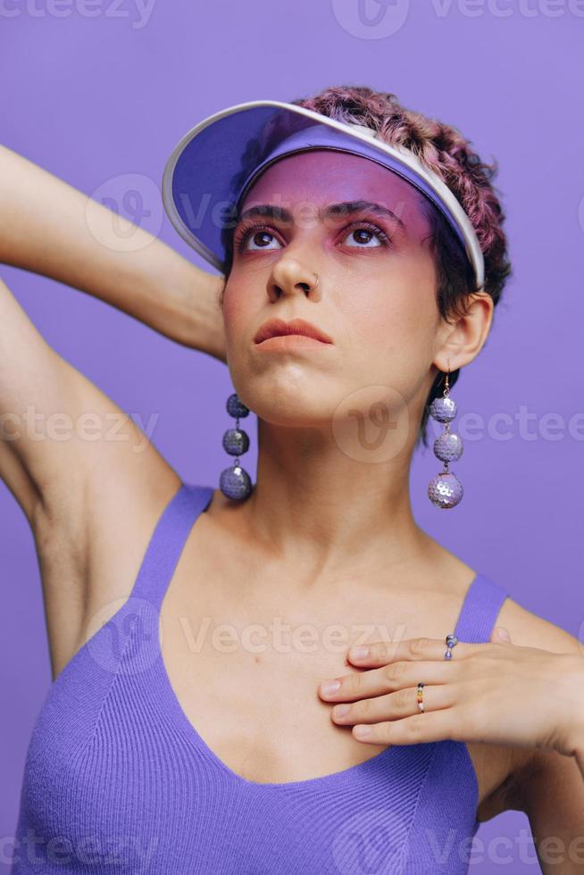 Portrait of a sporty fashion woman posing in a purple sports suit for yoga and a transparent cap on a purple background monochrome photo