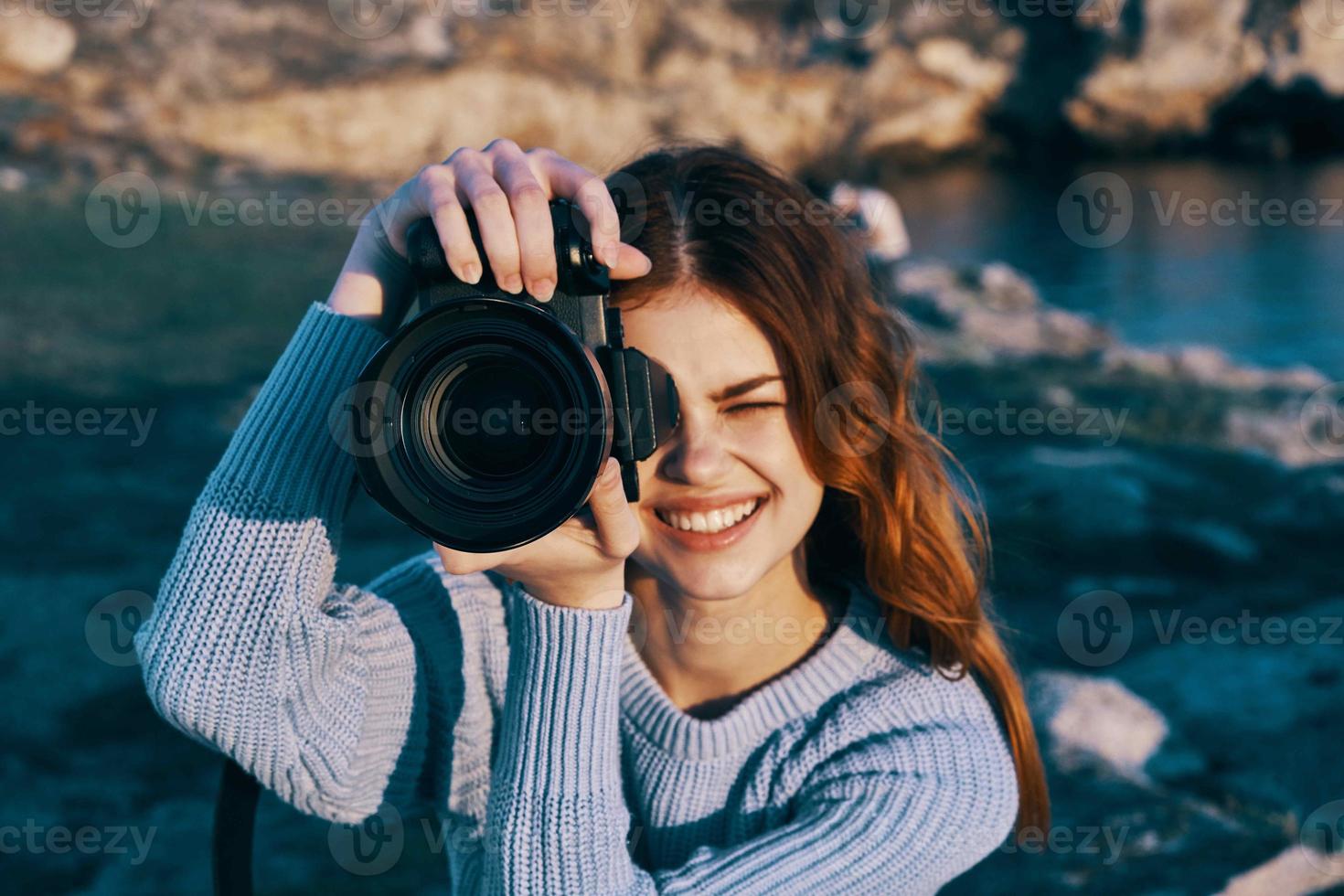 mujer con cámara en naturaleza tomando imágenes de paisaje profesional foto