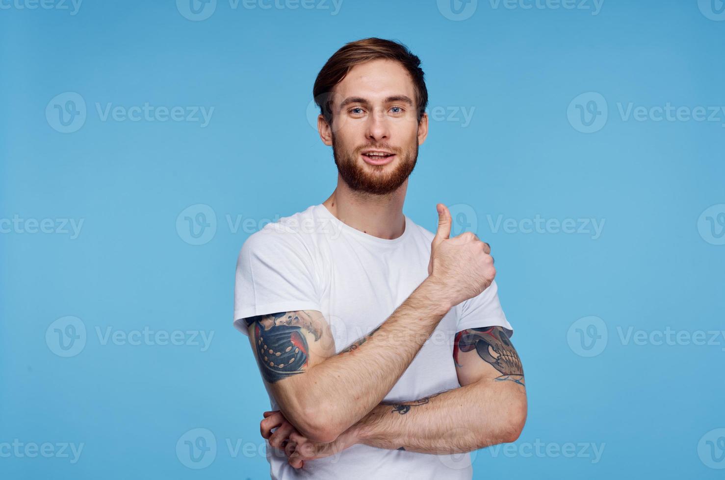 man in white t-shirt showing thumb up blue background studio photo