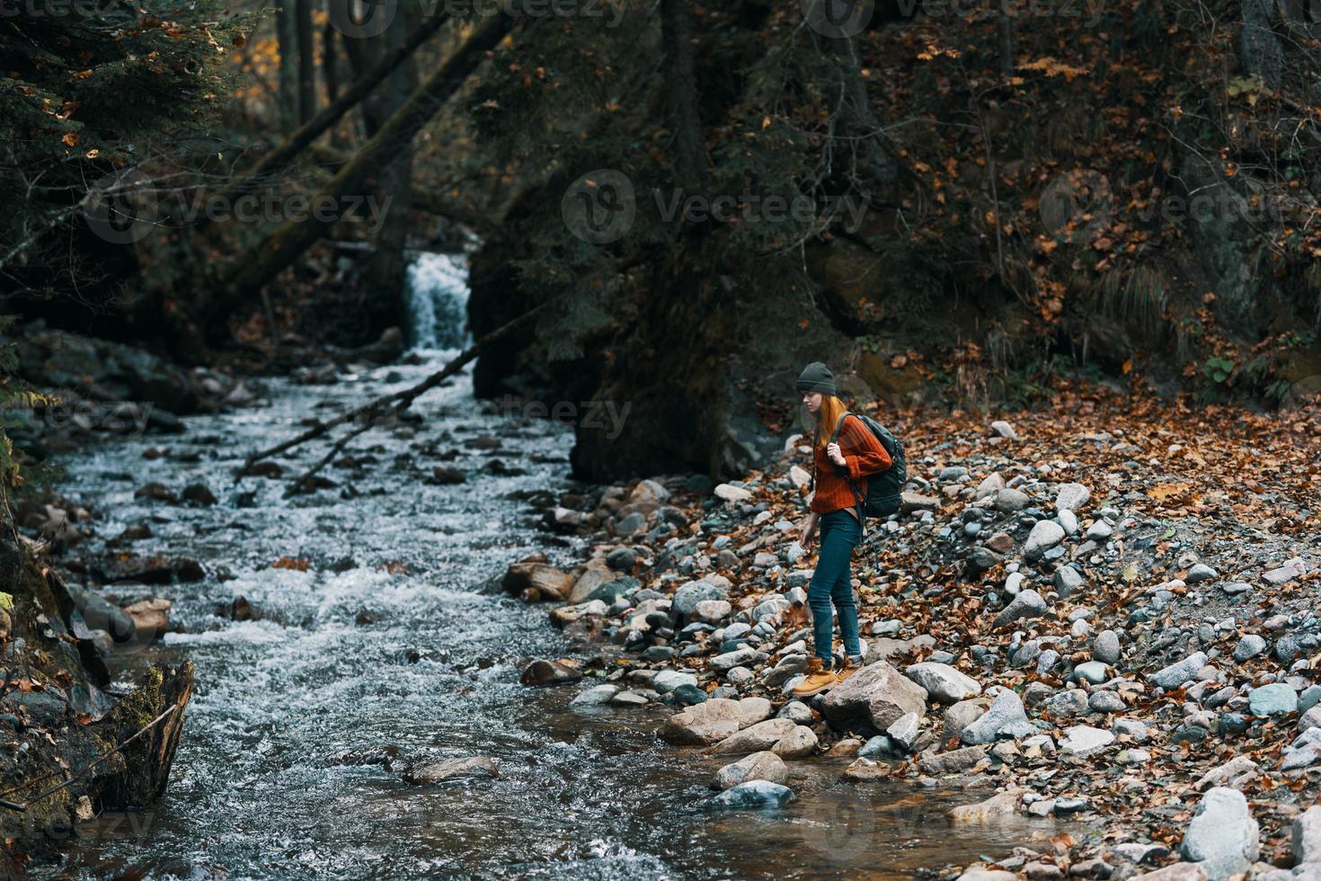 mujer viajes por el río en el montañas y un mochila en su espalda transparente agua bosque foto