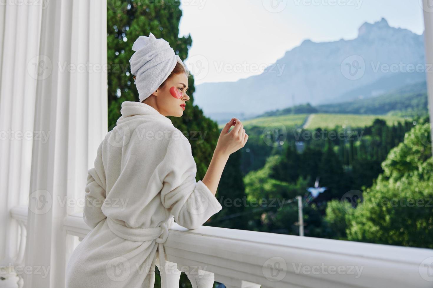 Sensual and beautiful woman in a robe stands on an open balcony Perfect sunny morning photo