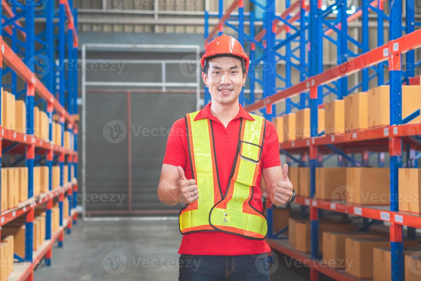 Cheerful male worker in hardhat smiling with giving thumbs up, Warehouse worker working in factory warehouse photo