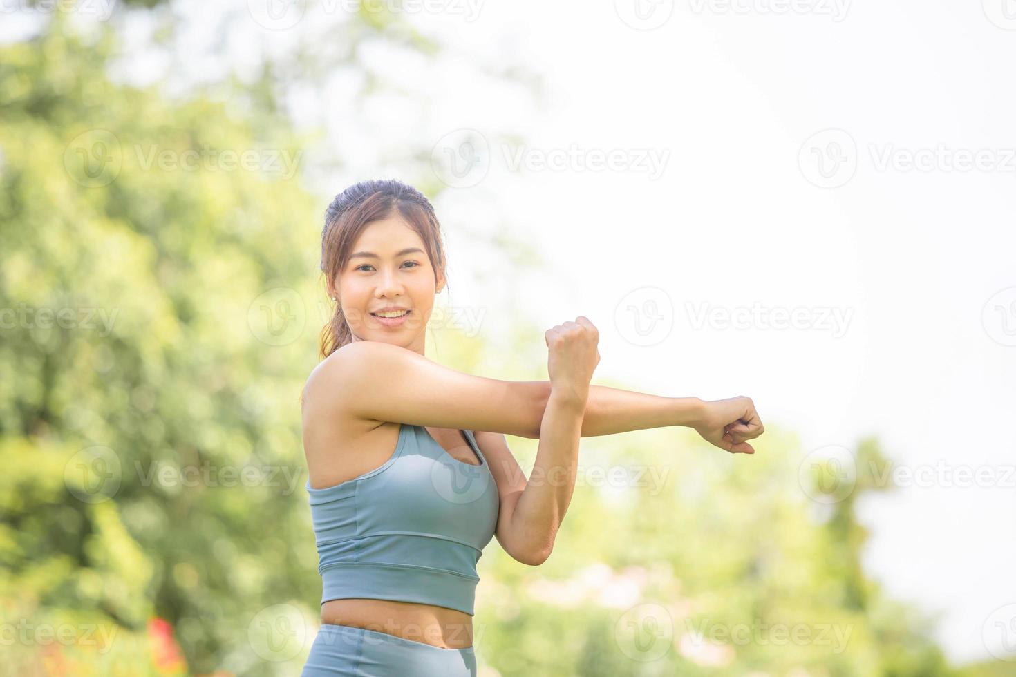 fitness mujer estirando los músculos antes de la actividad deportiva, mujer gimnasio en el parque ejercicio matutino, joven deportista haciendo ejercicio estira la mano y preparándose para correr foto