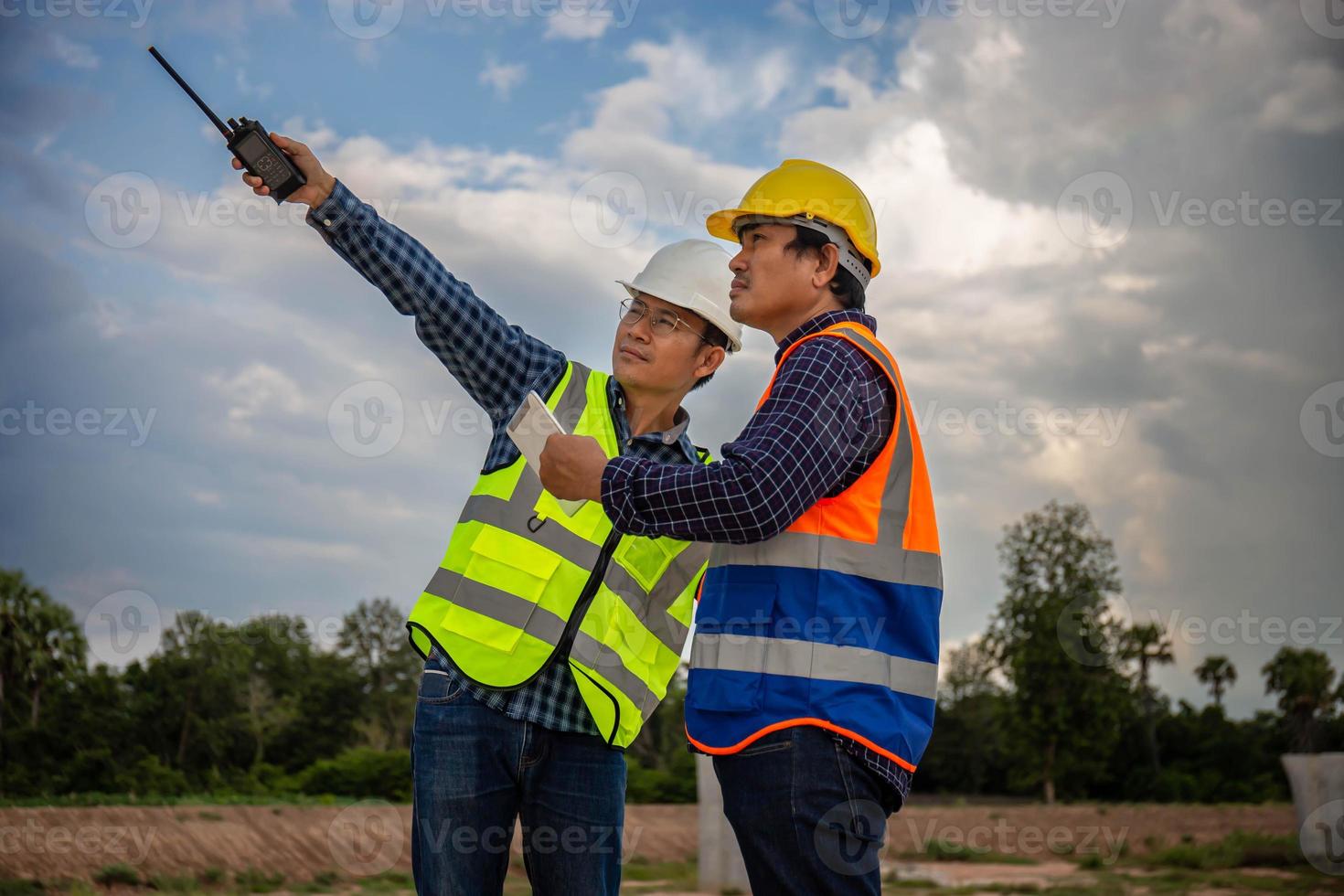Engineer and foreman worker checking project at building site, Engineer and builders in hardhats discussing on construction site, Teamwork concepts photo