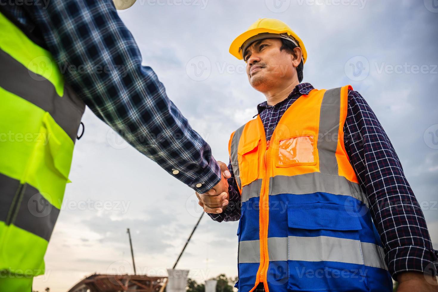Construction worker in protective uniform shaking hands with businessman at construction site, Engineers shaking hands at construction site photo