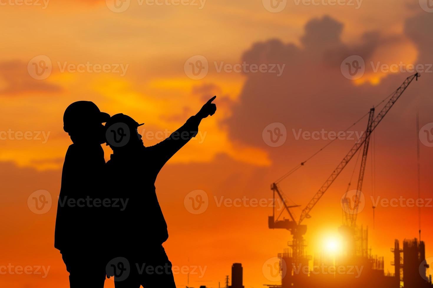 Silhouette of Engineer and worker checking project at building site background, construction site at sunset in evening time photo