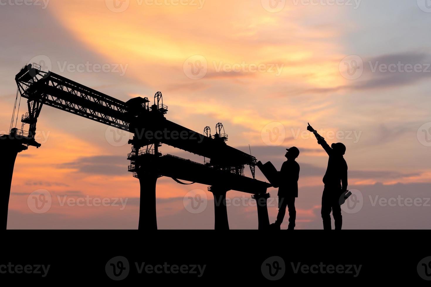 Silhouette of Engineer and foreman worker checking project at infrastructure construction site, construction site at sunset in evening photo