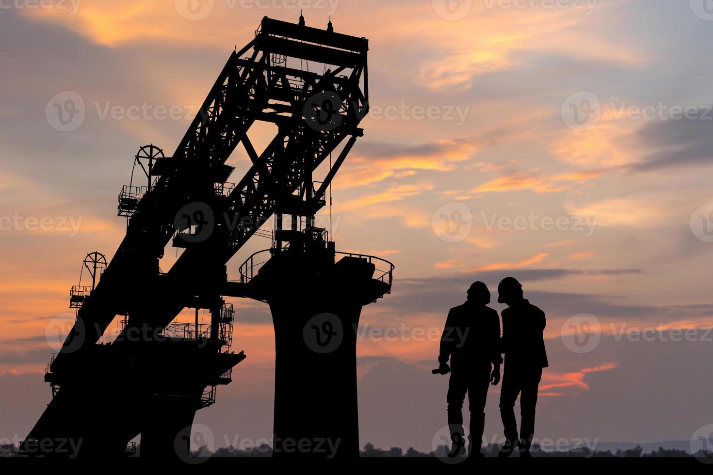 Silhouette of Engineer and worker with clipping path checking project at infrastructure construction site, construction site at sunset in evening photo