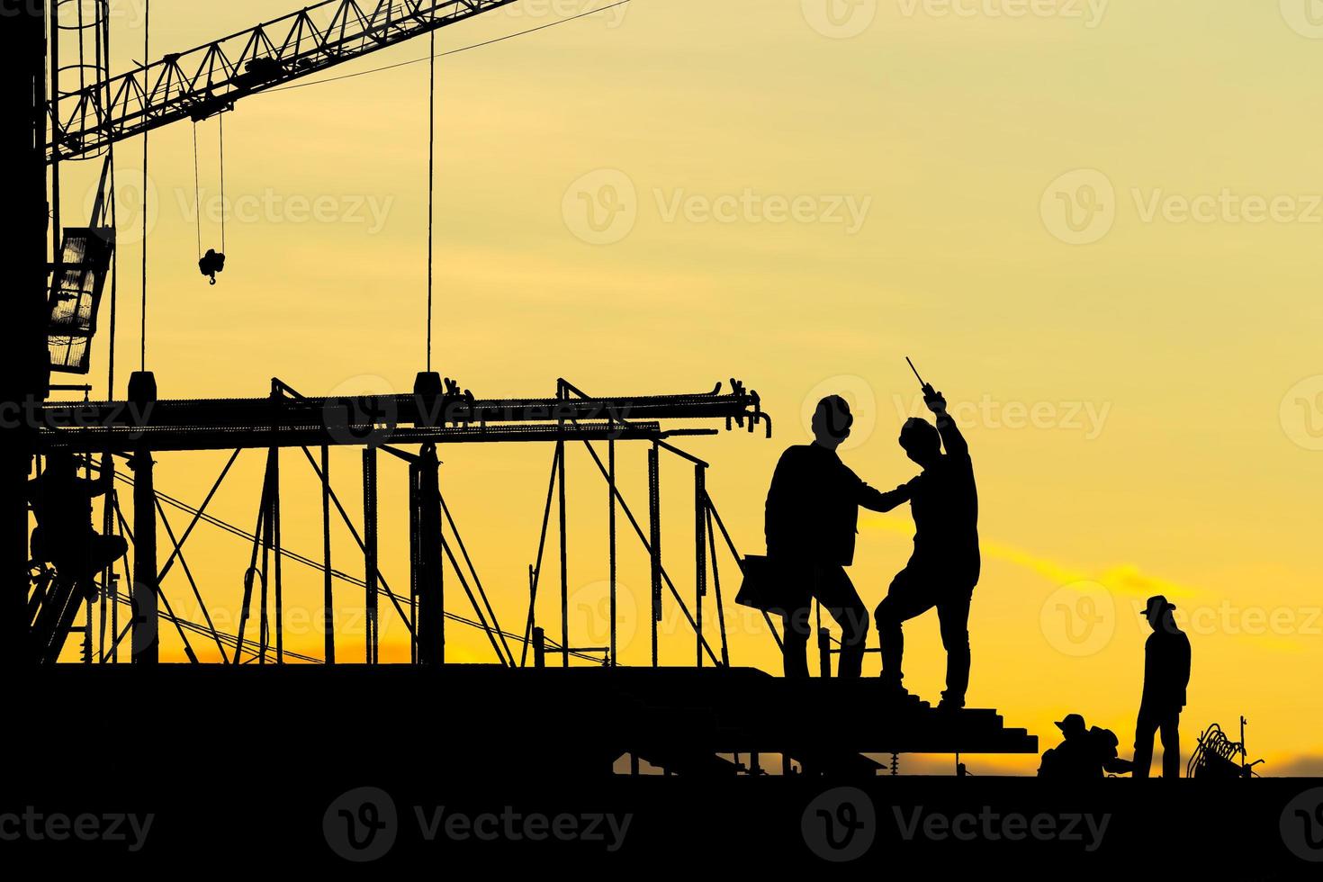 Silhouette of Engineer and worker checking project at building site background, construction site at sunset in evening time photo