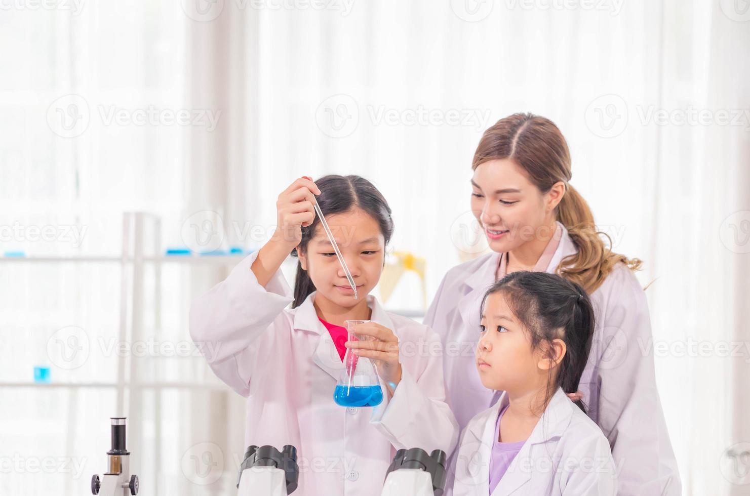 Elementary science class, Cheerful kid girl with teacher scientist in school laboratory, Science laboratory photo