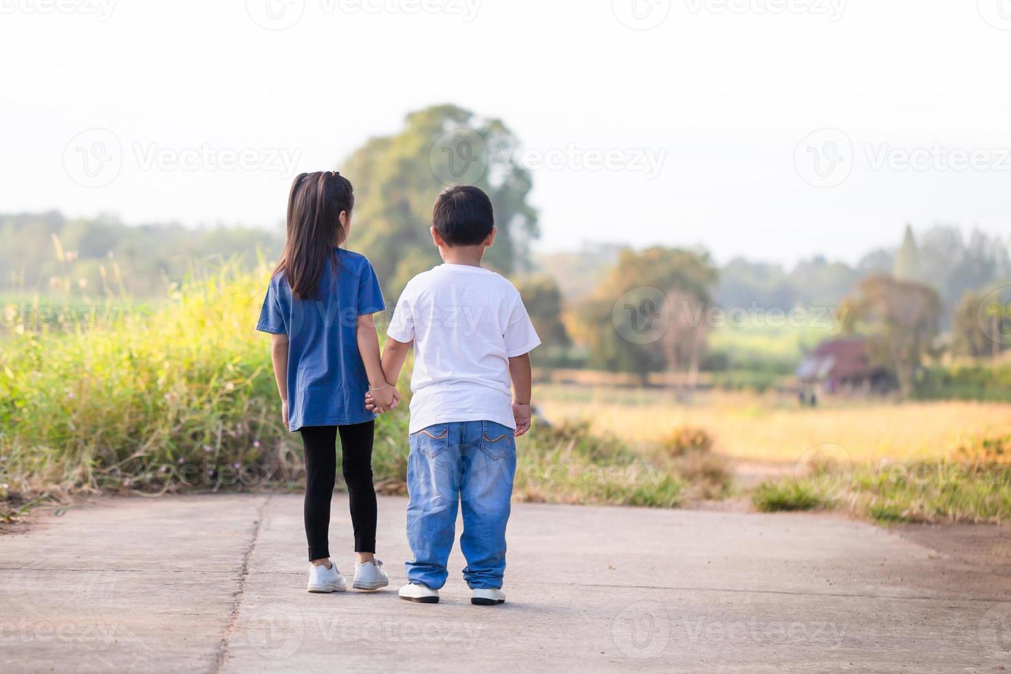 Happy children playing outdoors in park. Asian kids playing in garden, boy and girl holding hands photo