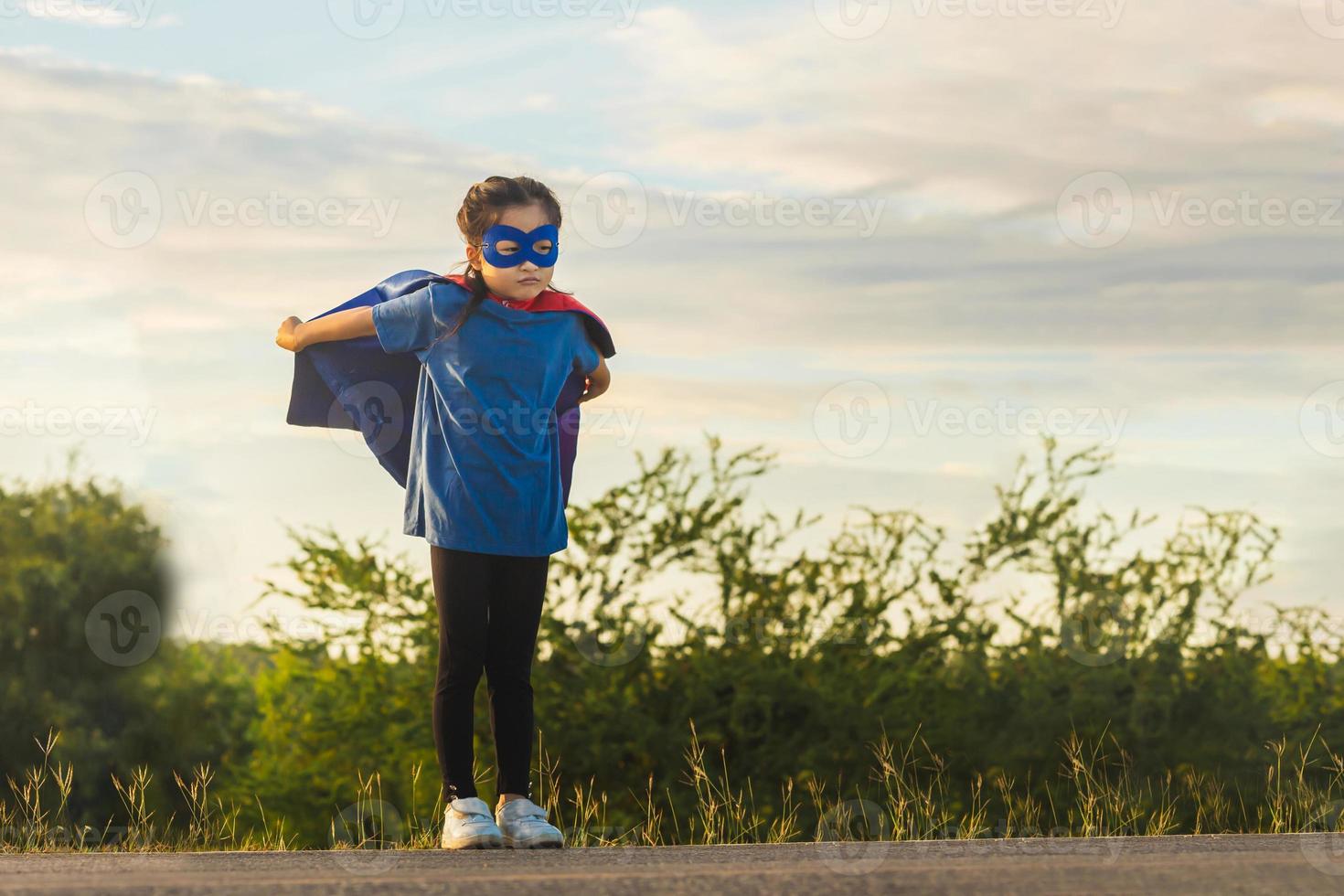 retrato de adorable niño niña teniendo divertido exterior. pequeño niño niña jugar superhéroe foto