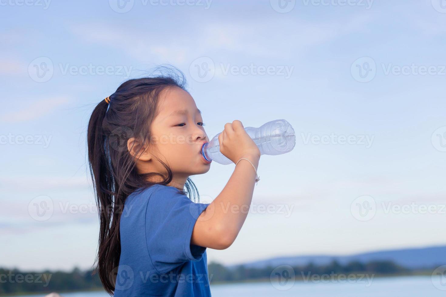 Asian child girl drinking water after playing outdoor photo
