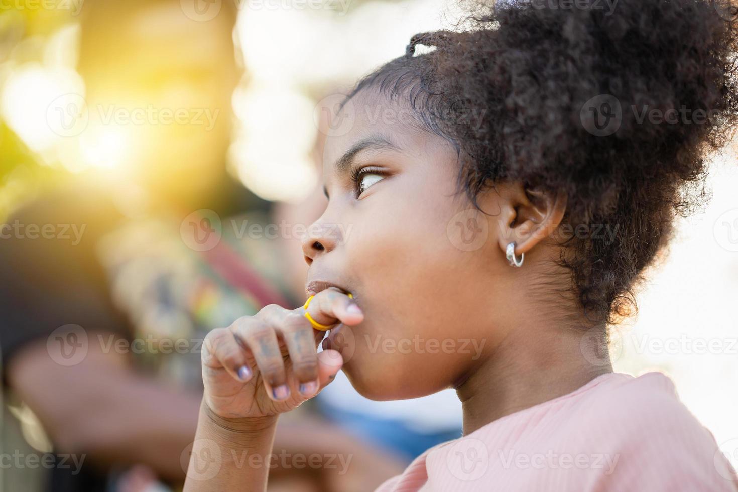 Kid girl with ring pop candy in the park, Girls enjoy ring candy pops, Children play outdoor photo