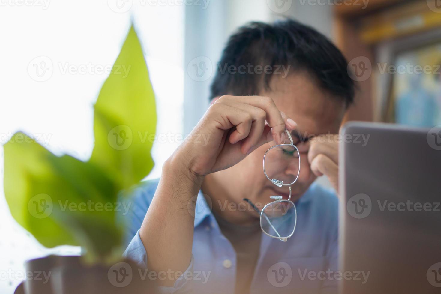 Asian man stressed while working on laptop at home, Working from home concepts photo