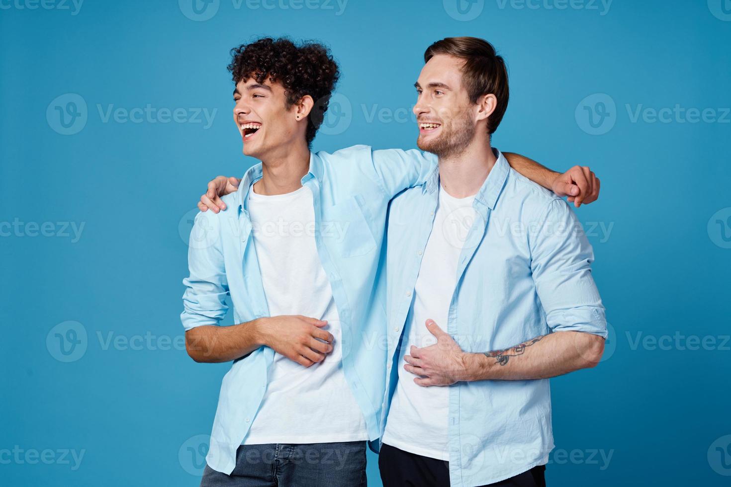 young men in identical shirts hugging on a blue background best friends fun photo