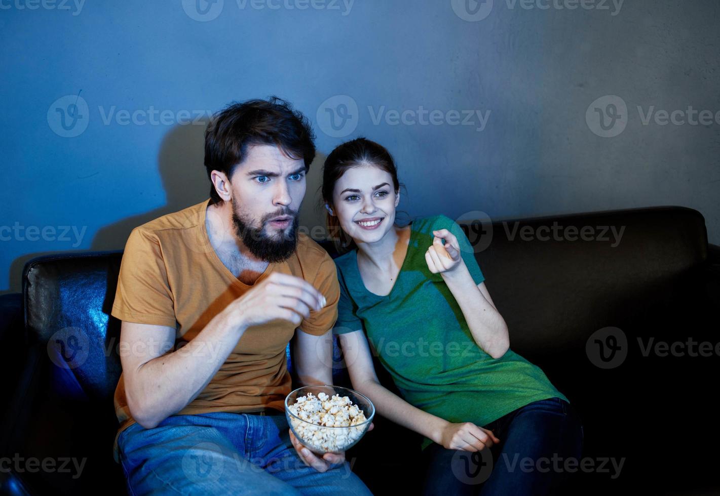 Emotional woman and man on the couch with popcorn watching TV photo