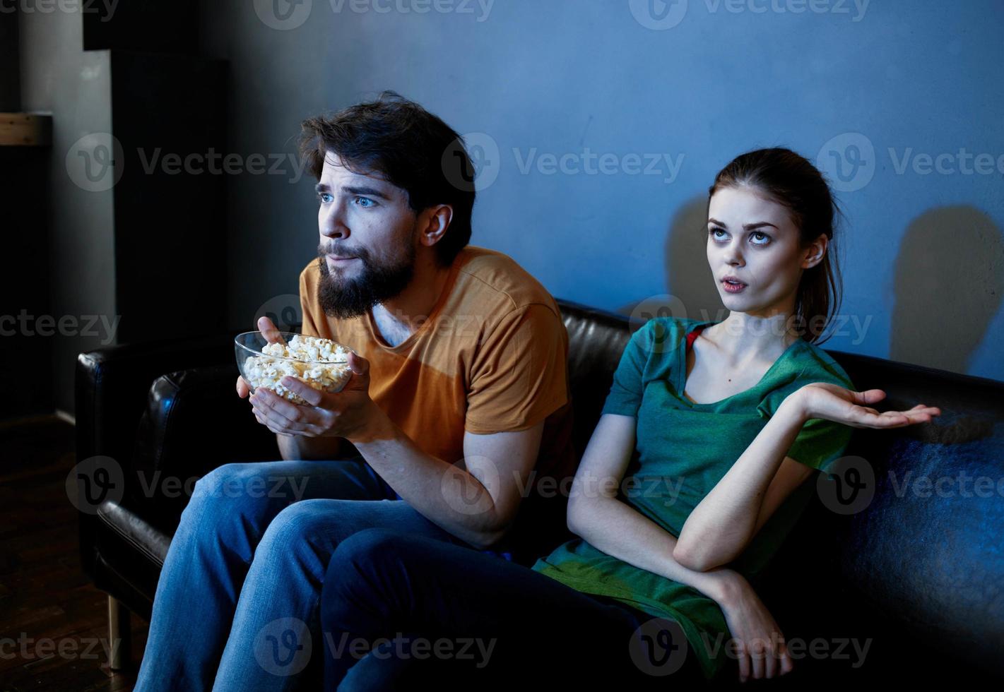 Men and women on the couch In a dark room watching a horror movie photo