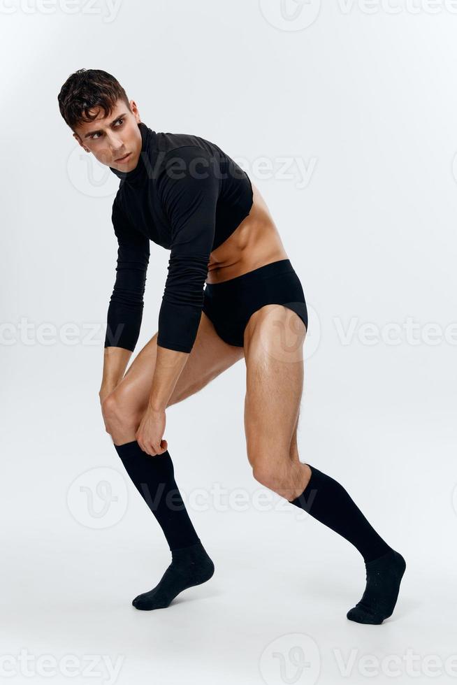 handsome guy with a pumped-up torso in shorts, socks and a sweater posing on a light background fashion style photo
