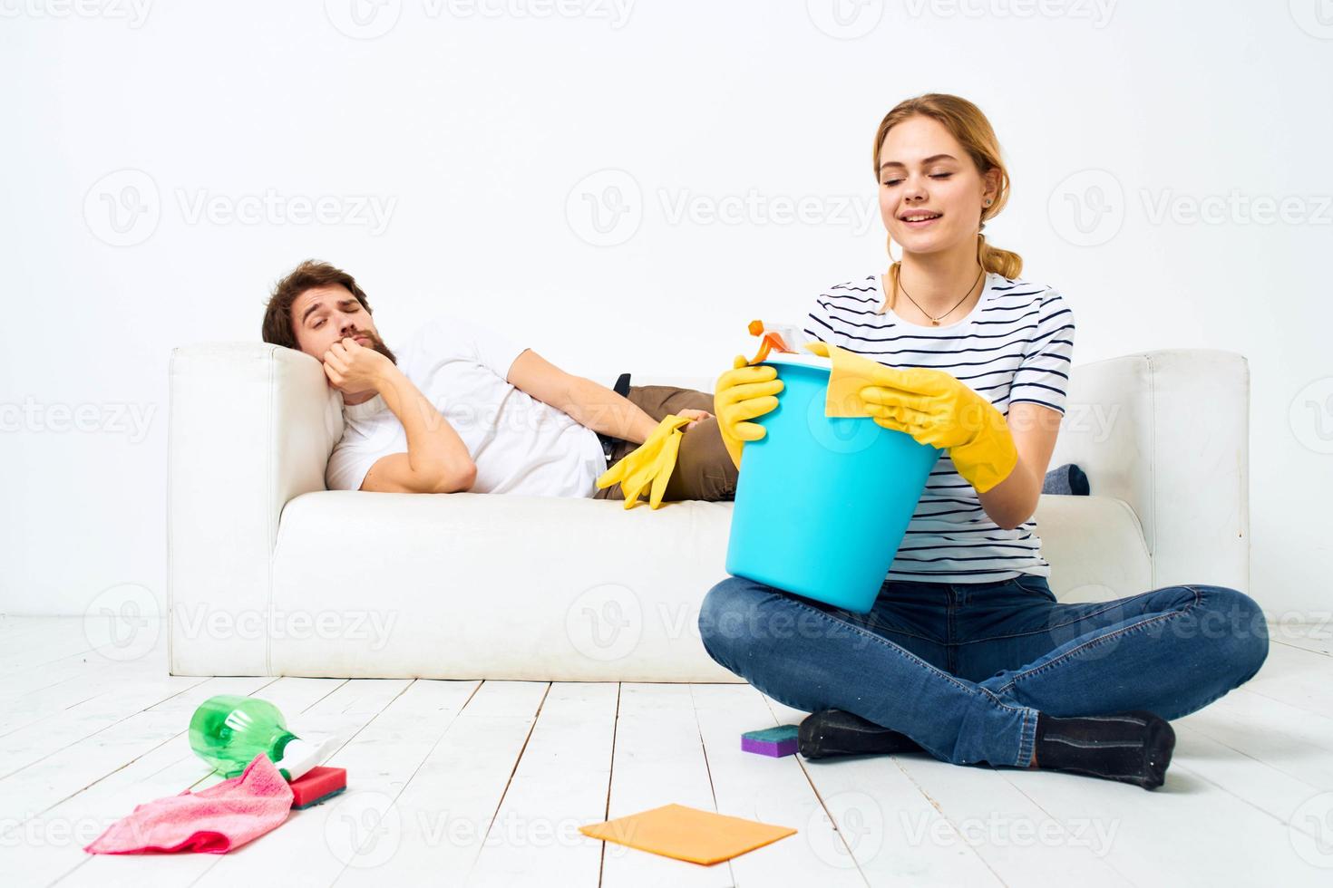 The husband lies on the couch while his wife cleans up the interior work photo