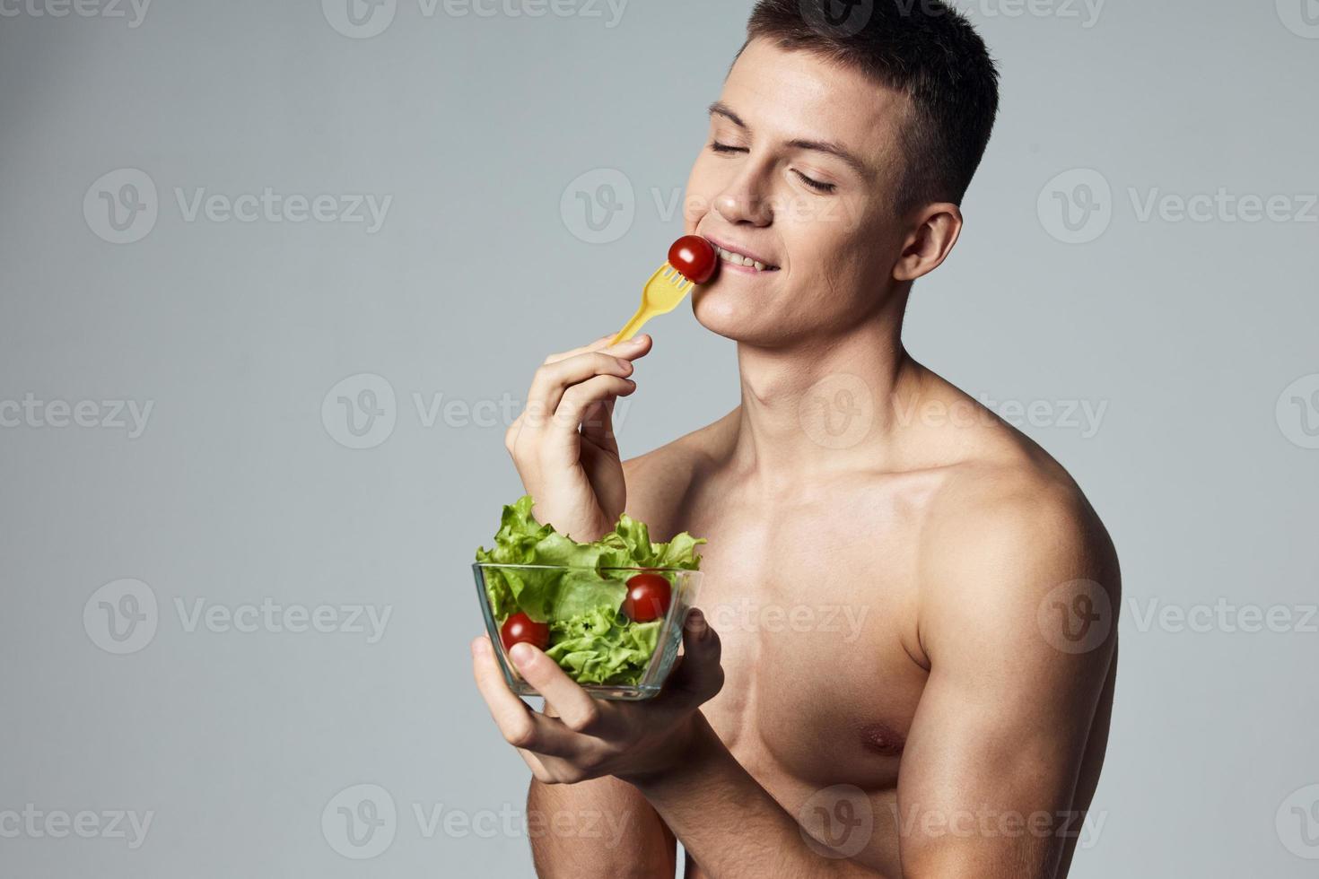 alegre hombre con muscular torso vegetal ensalada comiendo salud comida recortado ver foto
