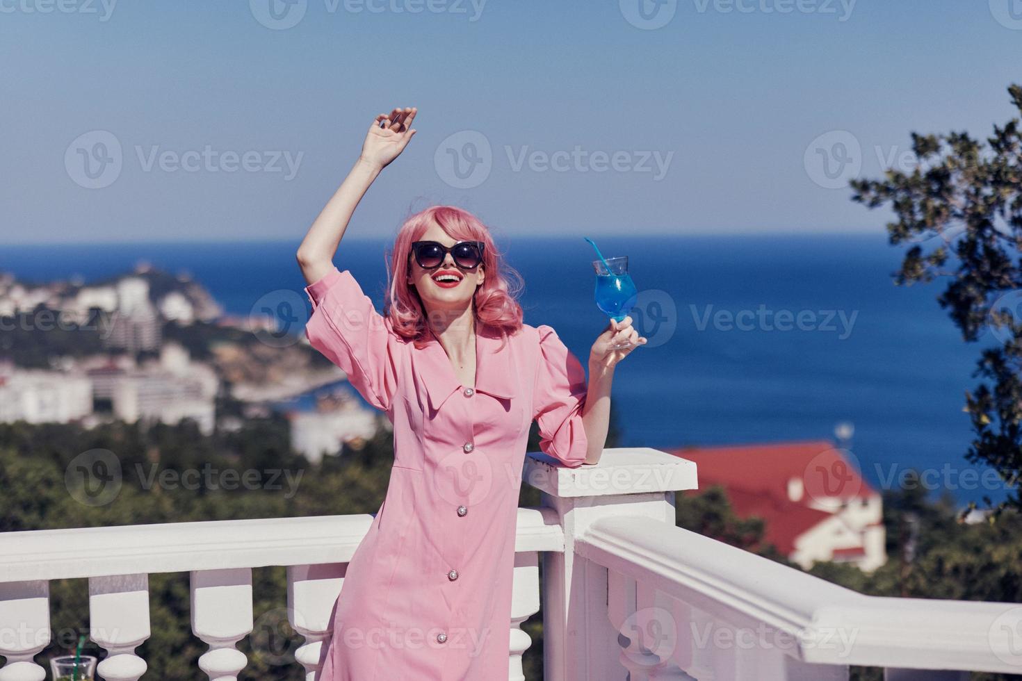 Delighted young girl in a pink dress in sunglasses with a cocktail Happy female relaxing photo