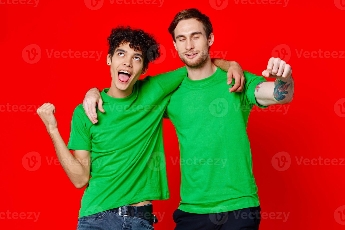 Two cheerful friends hug green t-shirts emotions communication red background photo