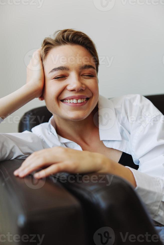 Women lying at home on the couch portrait with a short haircut in a white shirt, smile, depression in teenagers, home holiday photo