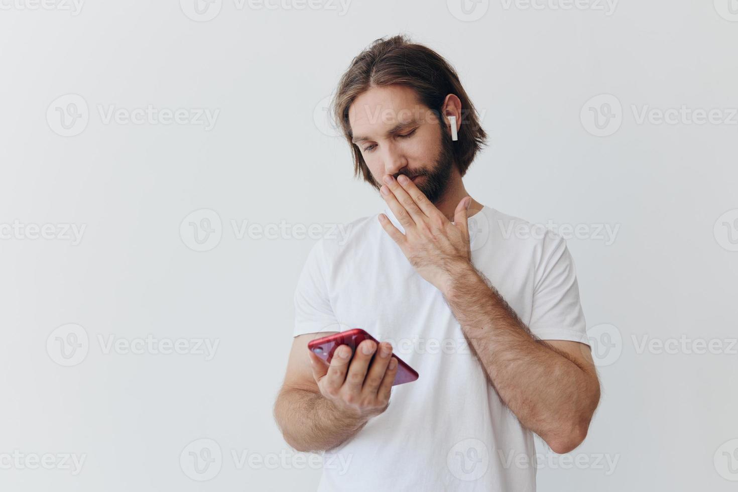 un hombre es participación un teléfono con inalámbrico auriculares en su orejas y leyendo un social medios de comunicación mensaje en línea persona de libre dedicación trabajo correspondencia en un blanco antecedentes foto