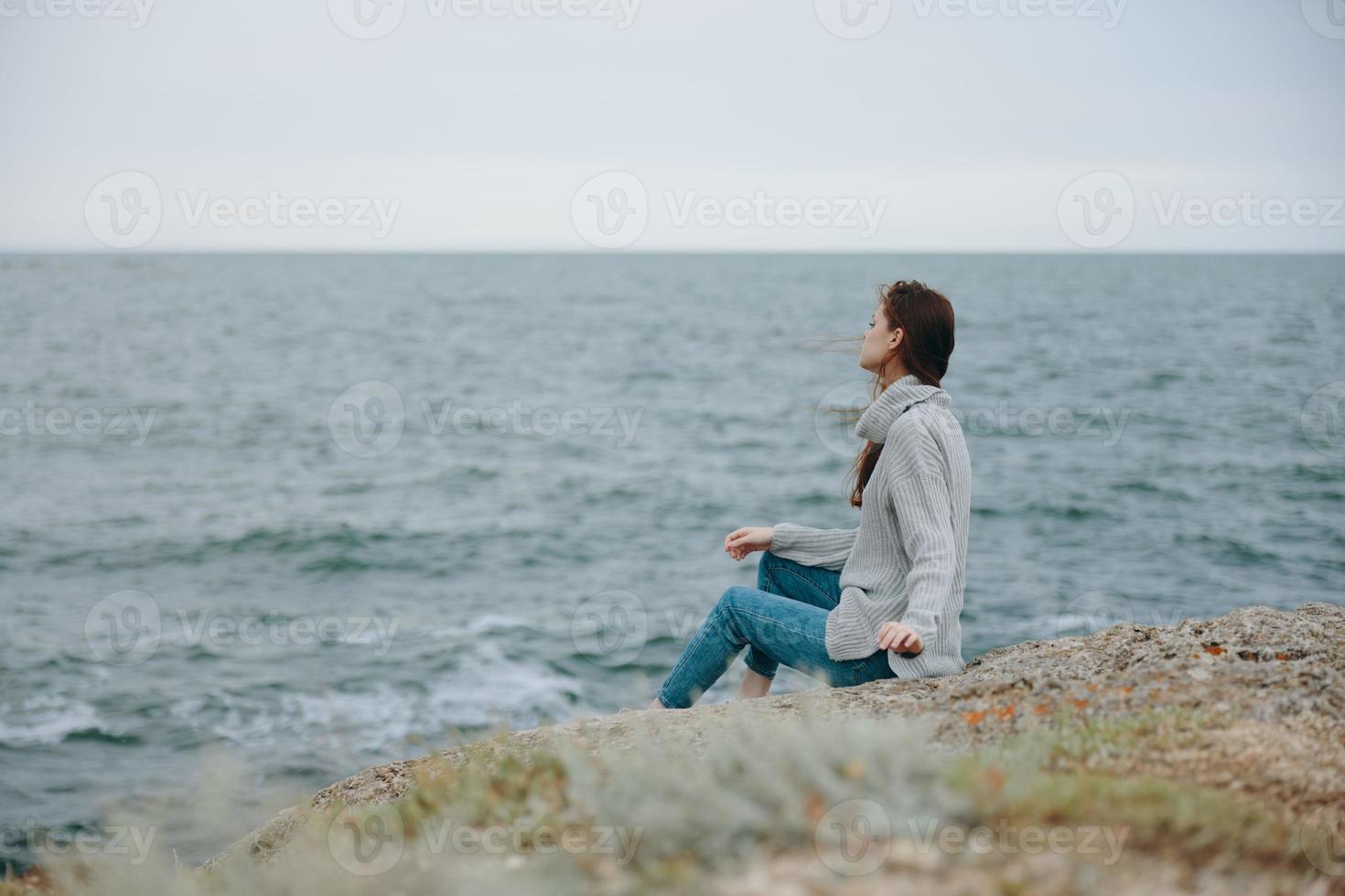 bonito mujer sentado en el costa suéter paisaje relajación concepto foto