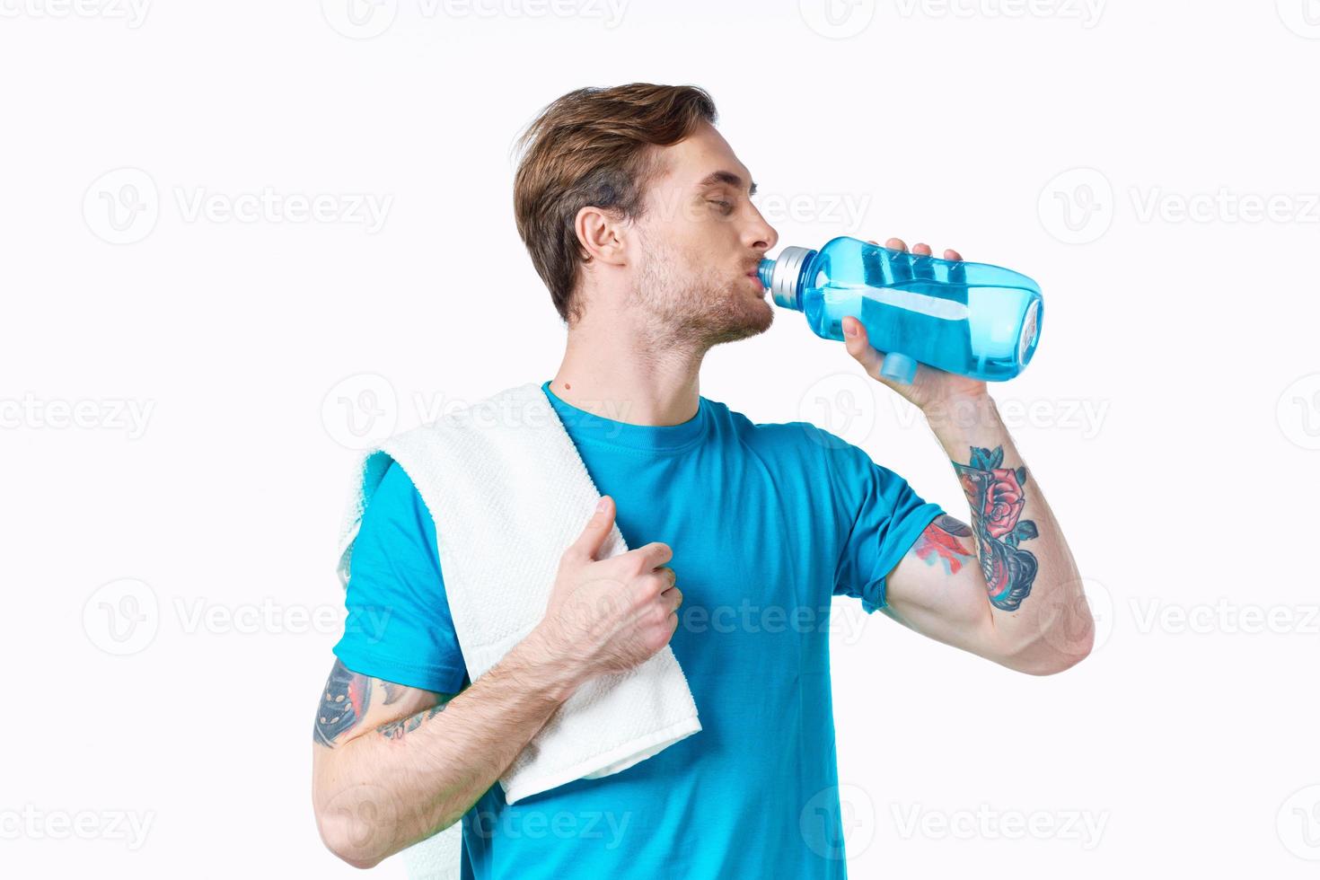 man athlete drinks water from a bottle on a white background and a towel on his shoulder photo