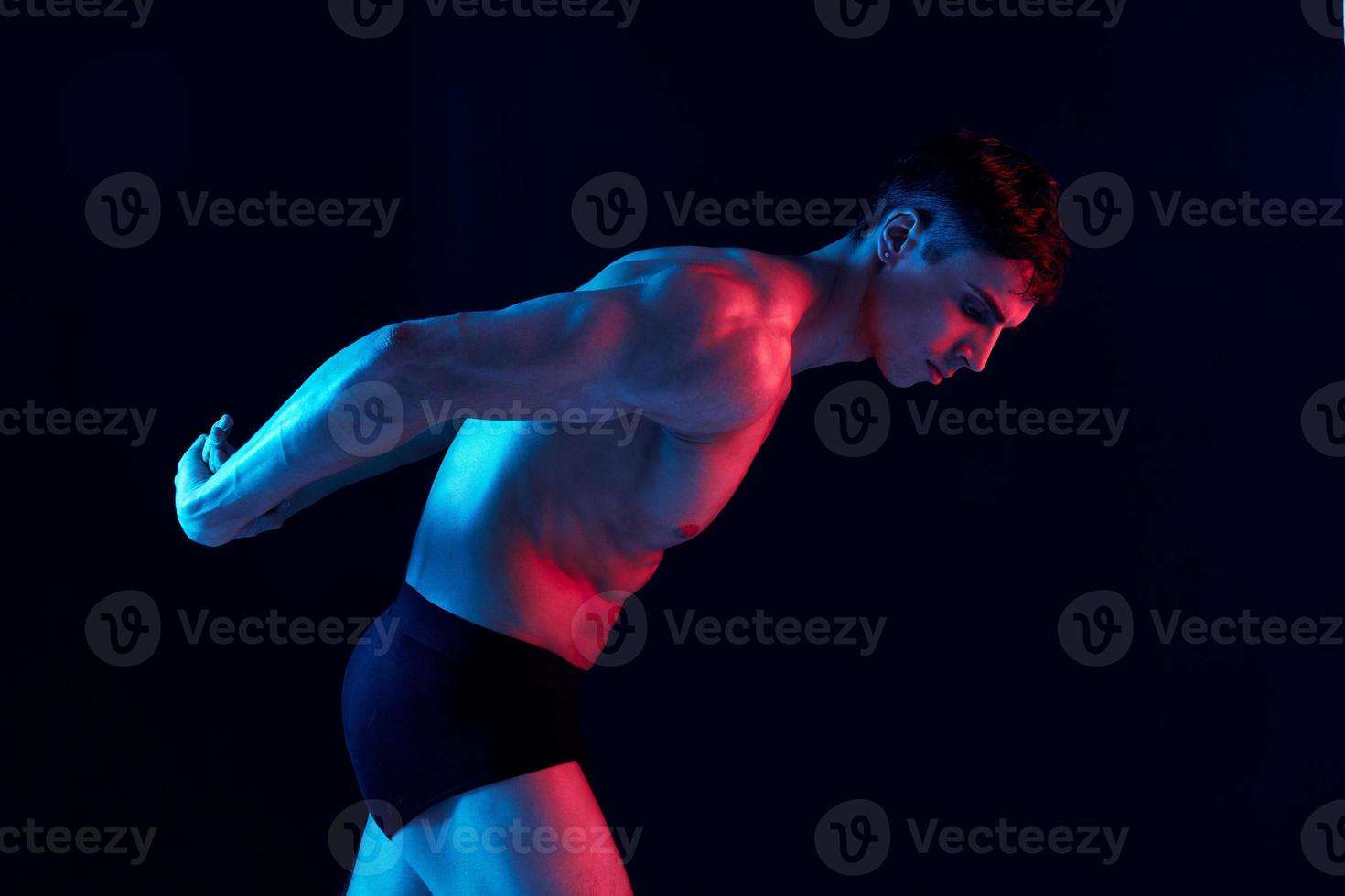 portrait of an athlete on a black background and neon light evening shade sunset model photo