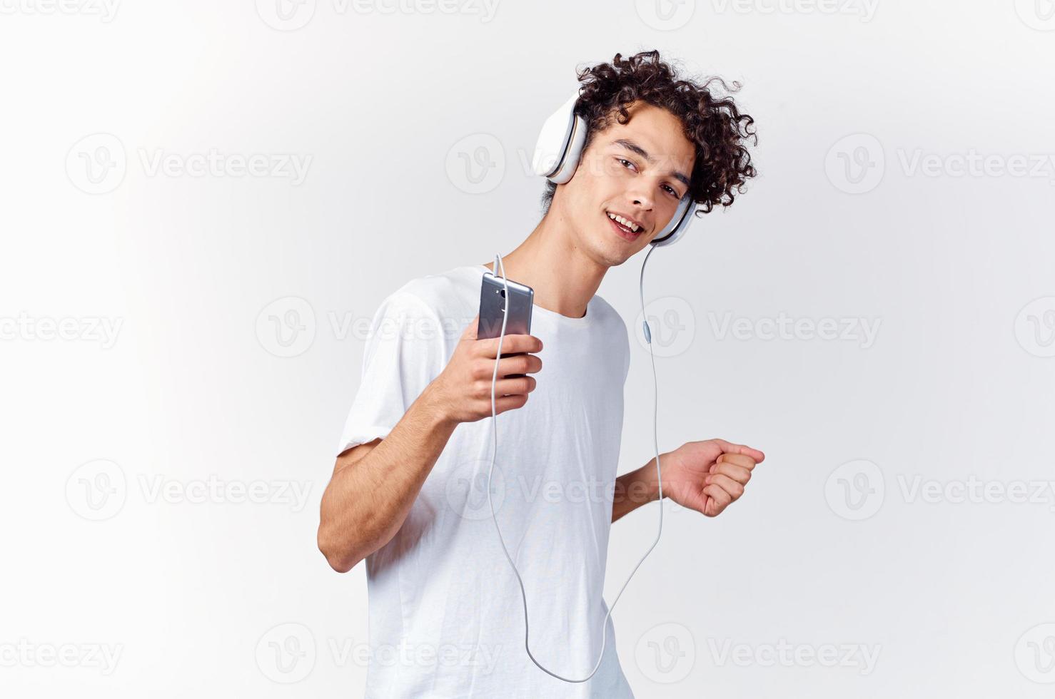 emocional hombre en blanco camiseta escuchando a música con auriculares recortado ver foto