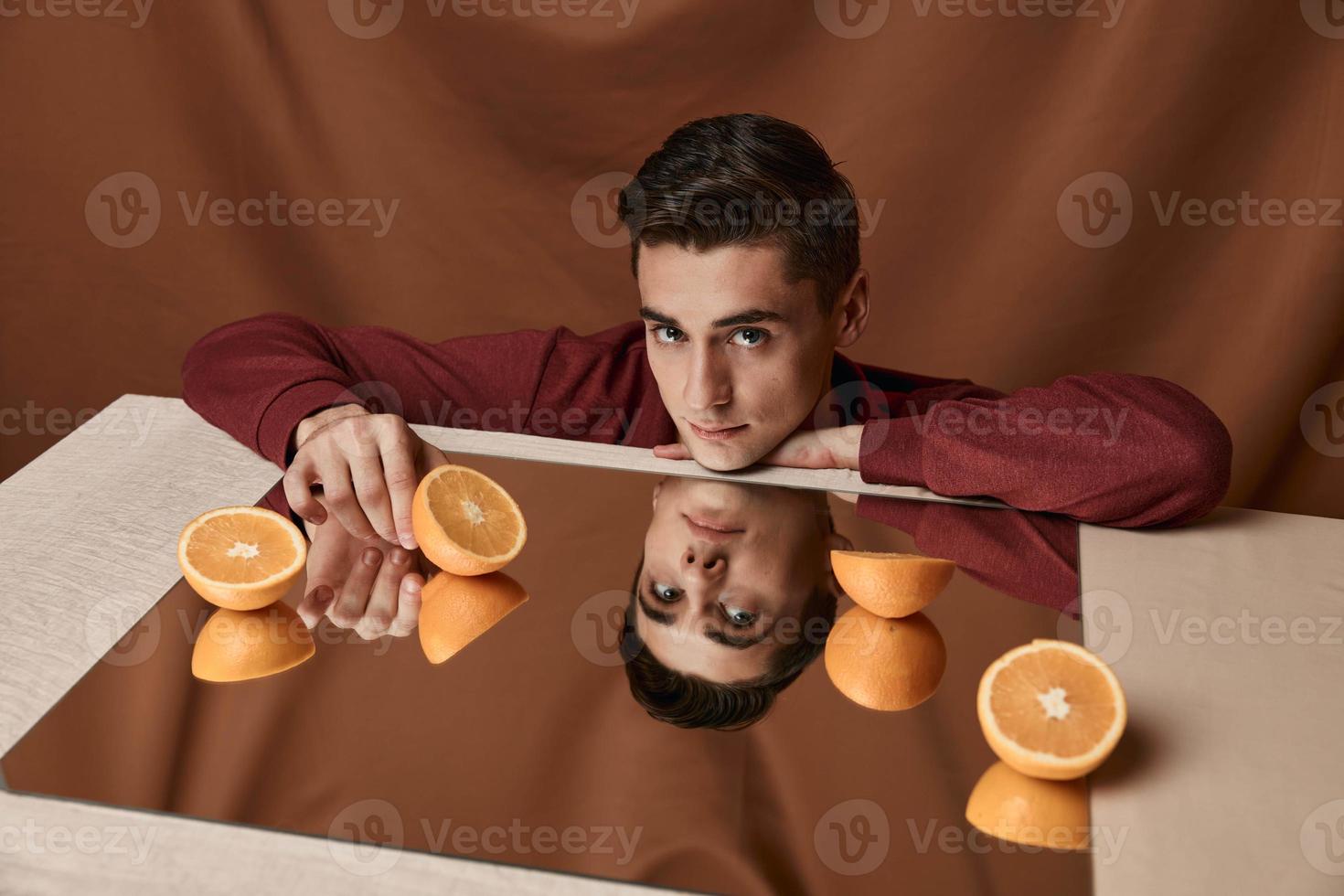 The man's face and the mirror on the table are orange oranges photo