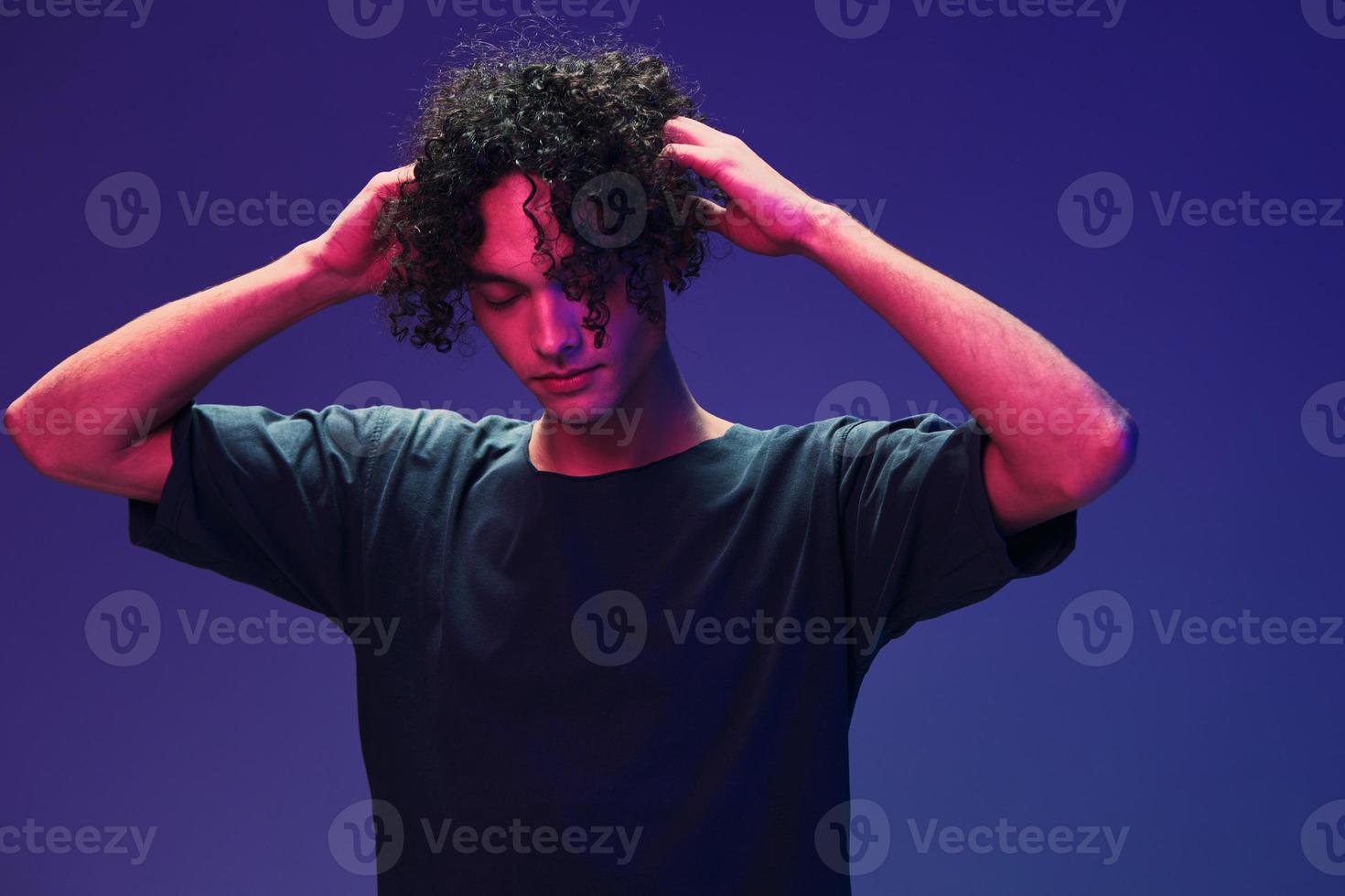 Relaxed stylish awesome curly man in black t-shirt posing isolated on color pink blue studio background. Cool fashion offer. Virtual Reality New Collection concept. Copy space for ad photo