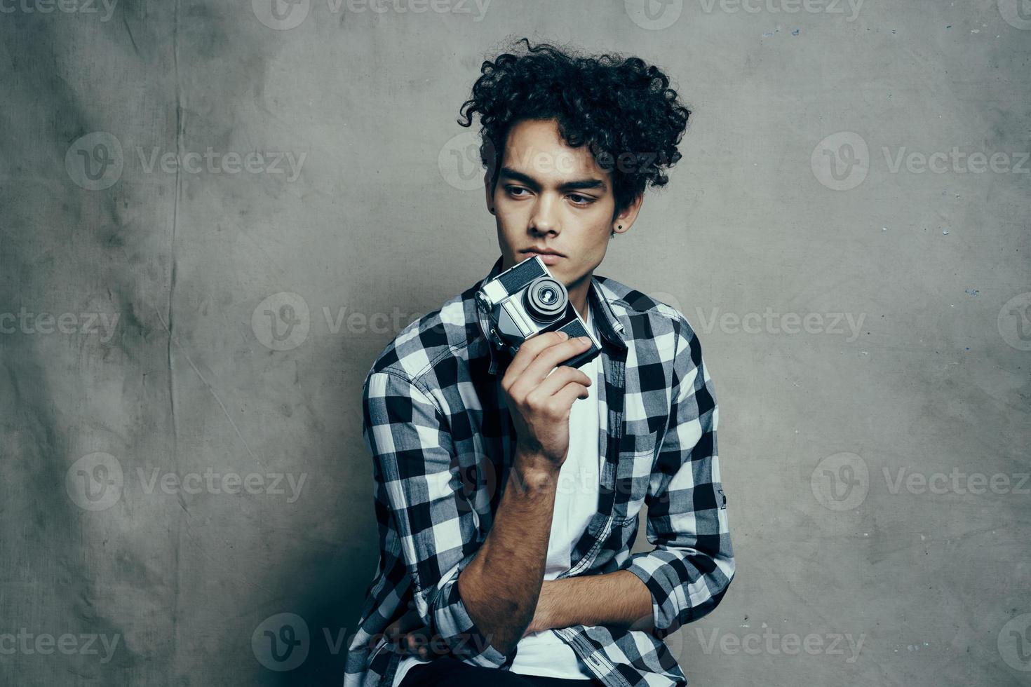 handsome male model in a shirt and a t-shirt on a gray background curly hair hairstyle camera Studio photo