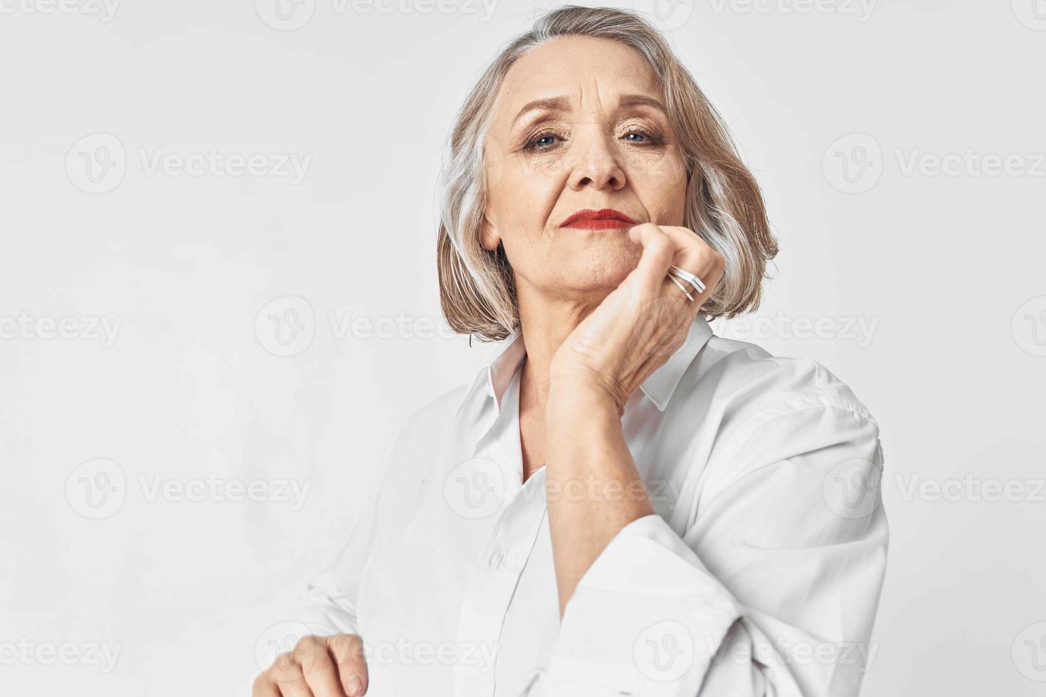 elderly woman in white shirt emotions light background photo