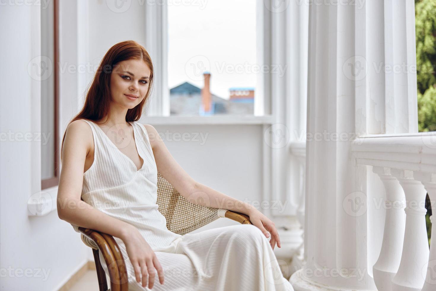 portrait of pretty woman in white dress sitting outdoors on the terrace photo