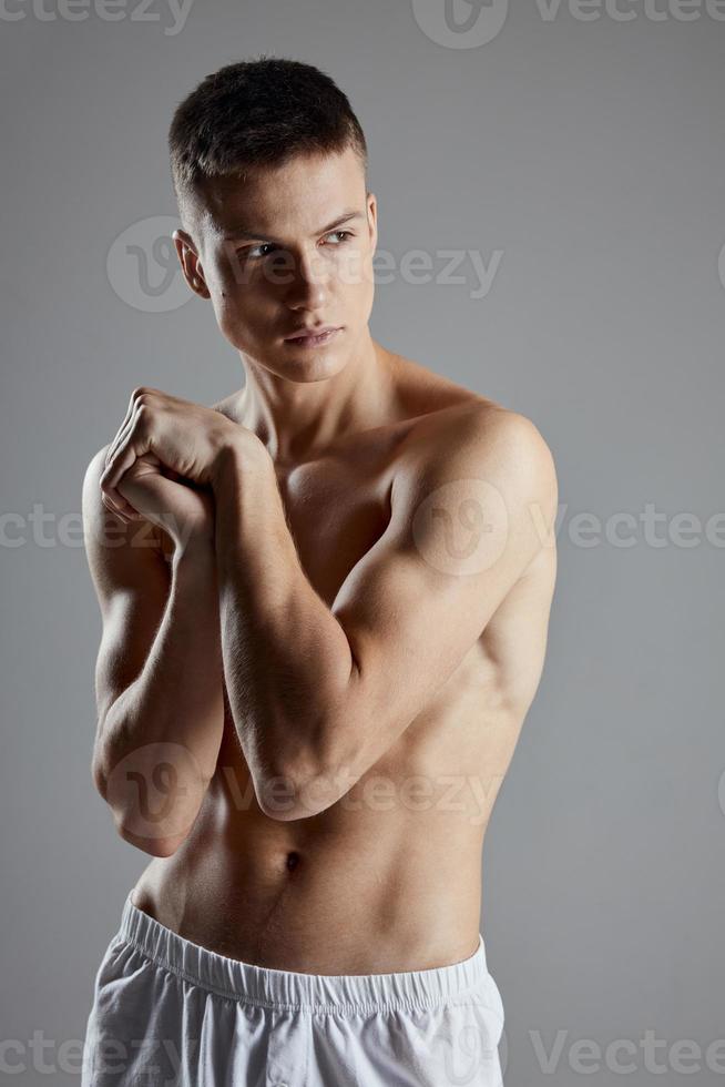 chico con atlético físico unido manos cerca hombro en gris antecedentes recortado ver foto