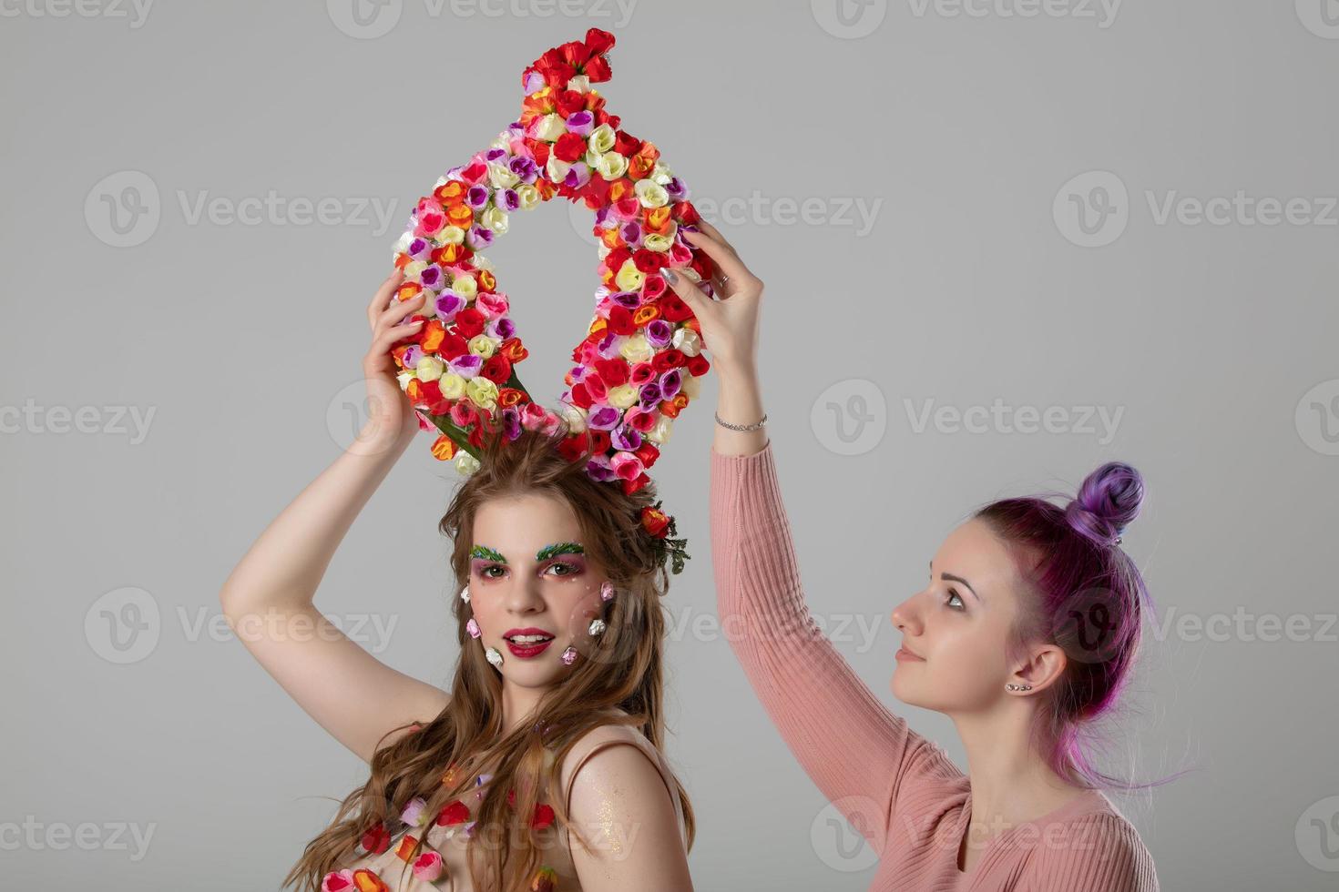 estilista y modelo. lujo niña modelo con flor cuernos y niña estilista. el trabajo de el diseñador. foto