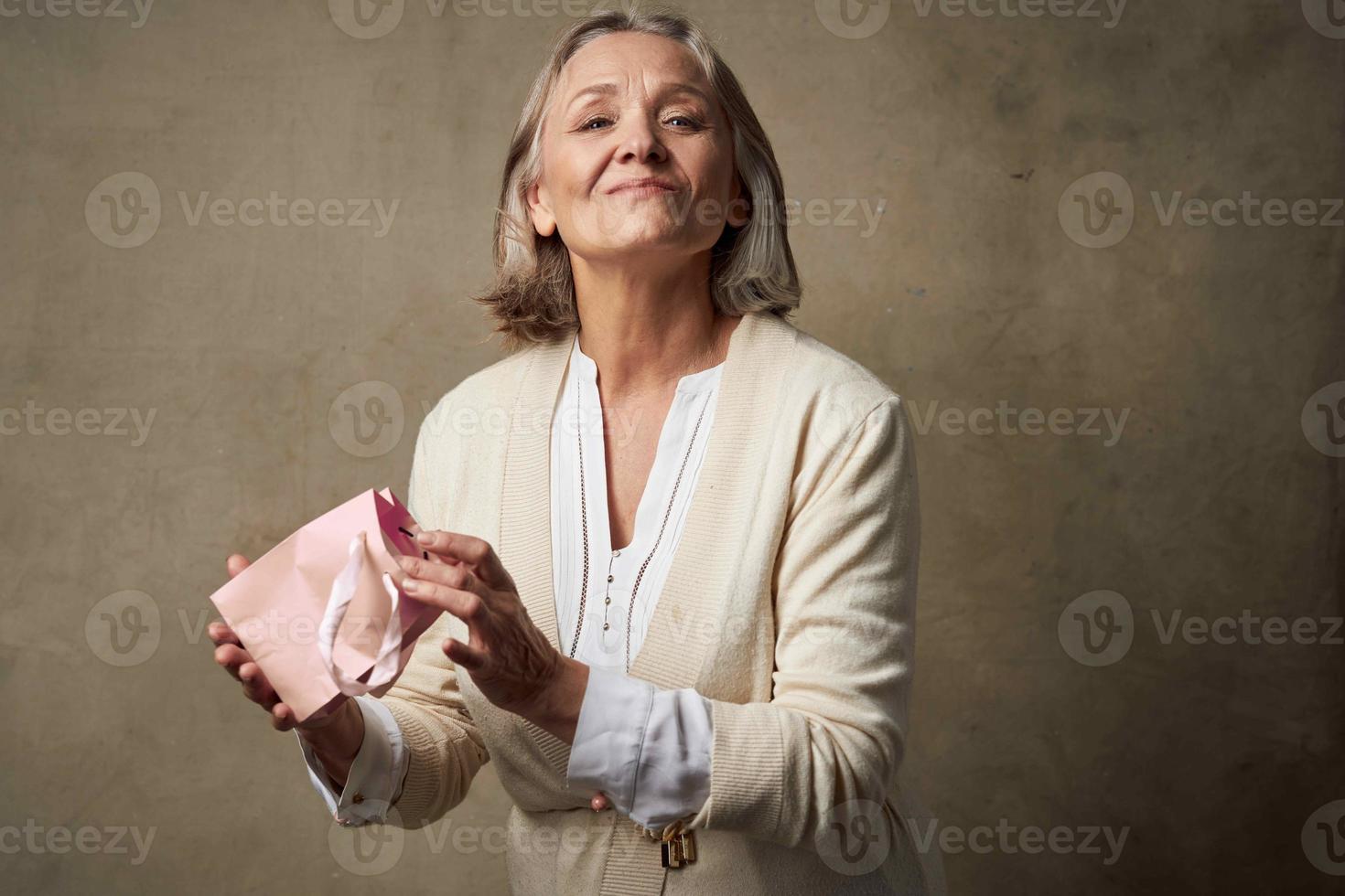 elderly woman in a dressing gown with a gift in her hands birthday care photo