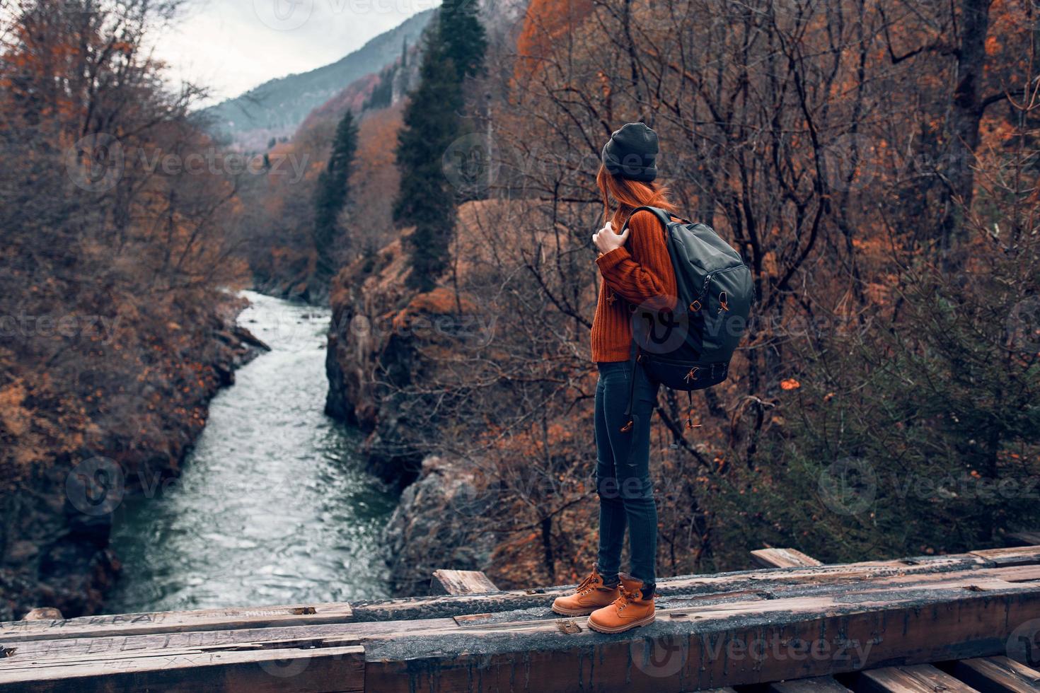 woman stands on a bridge over a river in the mountains Autumn forest travel photo