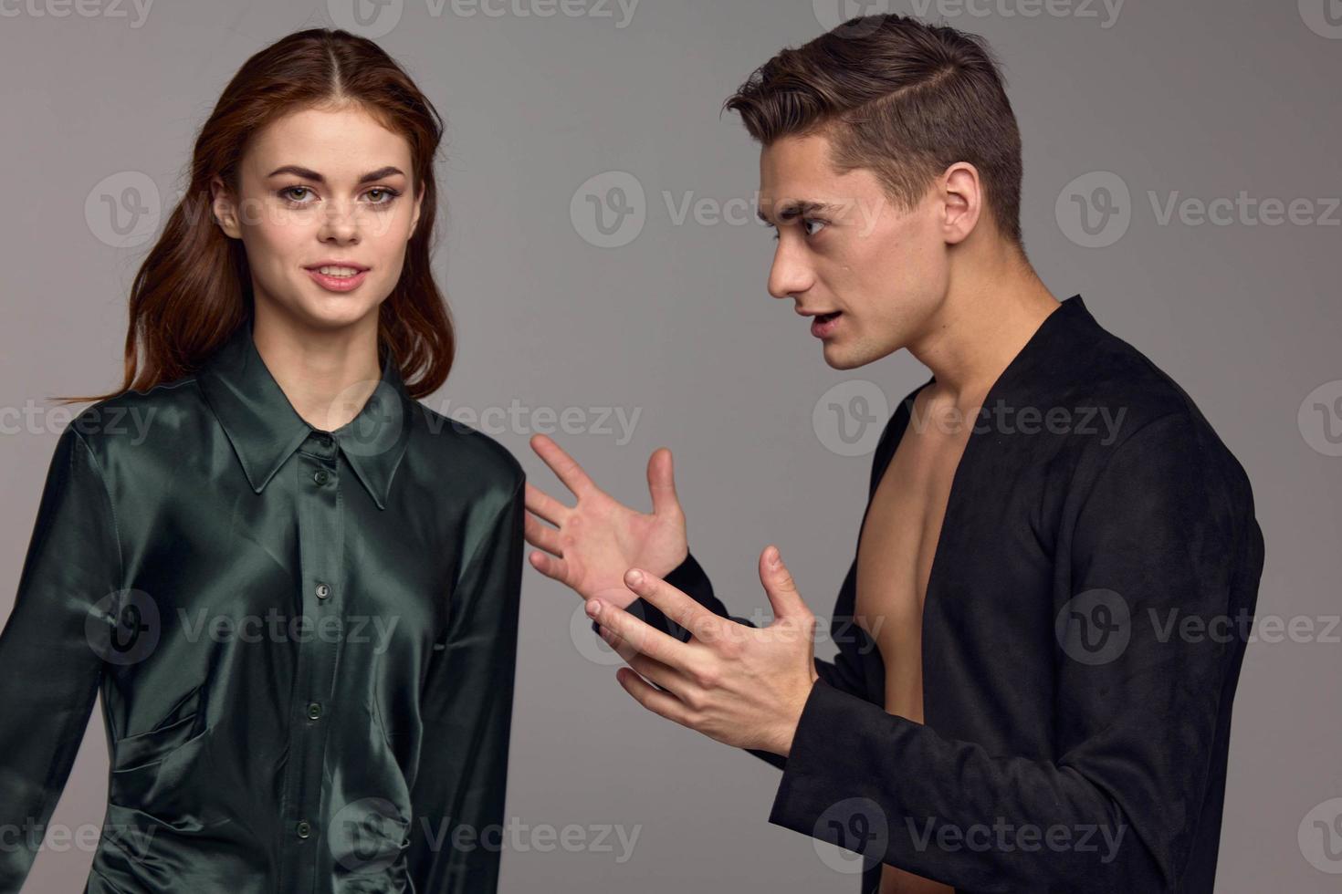 Man gesturing with his hands and looking at woman in dress on gray background cropped view photo